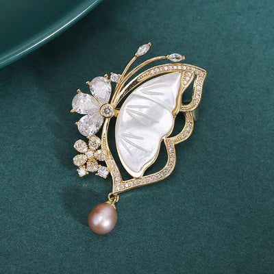 Front view of the white shell butterfly brooch with pearl drop decorative clothing pin on a white background
