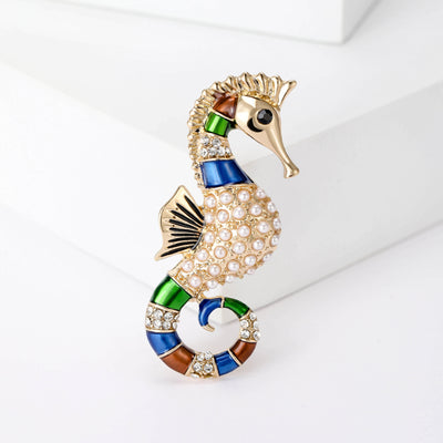 Product display showing a curled gold-tone seahorse with pearls and blue-green enamel accents