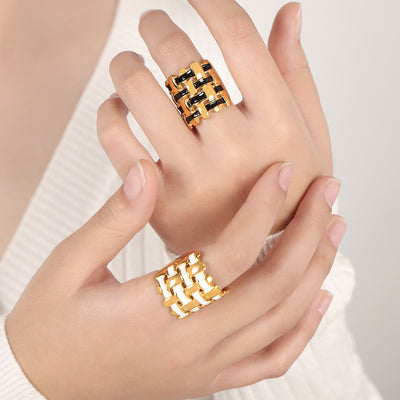 Hands wearing gold black and gold white basket weave enamel rings