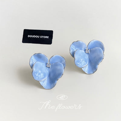 Light blue enamel flower petal studs beside black DOUDOU STORE tag