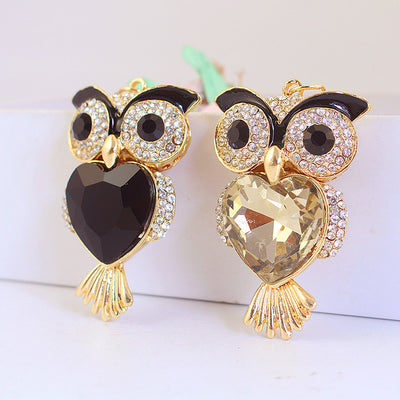 Two owl pendants display black and champagne faceted hearts with clear stone trim.