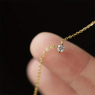 Product view showing a fine gold-tone chain centered by one small round clear stone