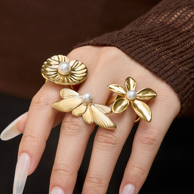 Styled hand view of oversized pearl center flower rings in main image 1.
