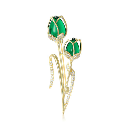 Front view of green double tulip bud brooch with long gold tone stems against a white background.
