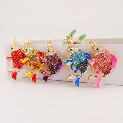 Five jeweled fish charms in red, gold, purple, blue, and pink displayed together.