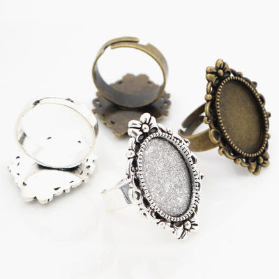 Adjustable ring blank with an ornate oval cabochon tray in a group view on a white background
