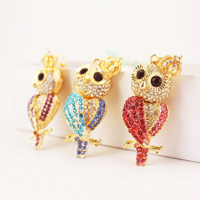 Three gold-tone crowned owl charms display pink, blue, and purple stone patterns.
