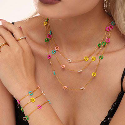 Layered gold flower bead necklaces and bracelets worn on model