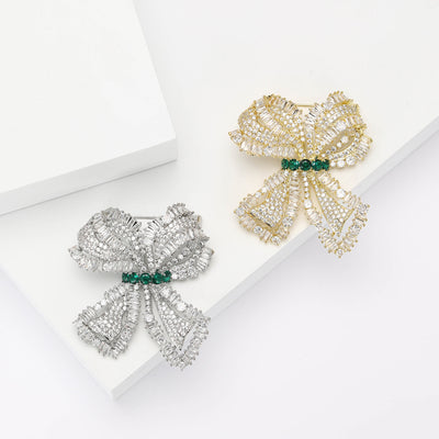 Silver and gold pave zircon bow brooches with green centers