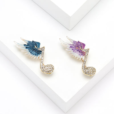 Front view of winged music note crystal brooch in blue and purple
