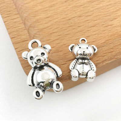 Antique silver bear charms arranged on a light background