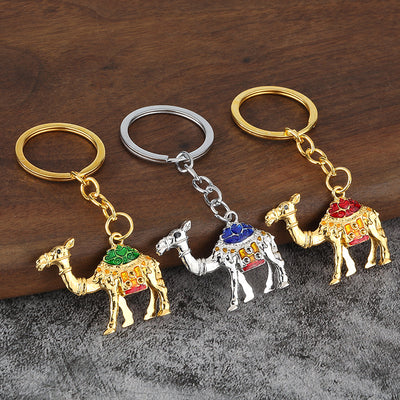 Three camel keychains with gold-tone and silver-tone bodies and green, blue, and red saddle details.