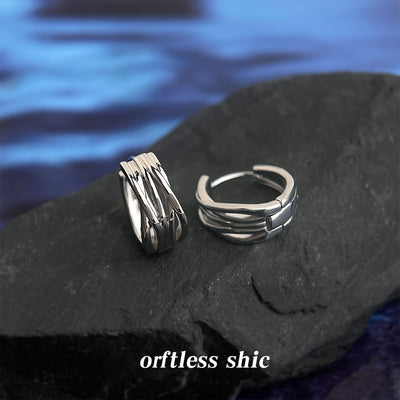 Silver multi-band crossed huggie hoops on dark stone