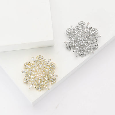 Gold and silver pearl snowflake brooches on white blocks