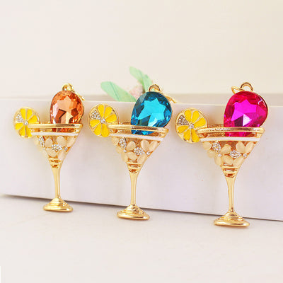 Three gold-tone cocktail glass charms display peach, blue, and pink faceted centers.