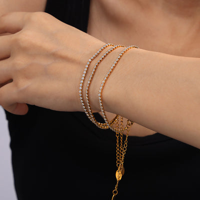 Gold zircon tennis bracelets stacked on model wrist with extension chains