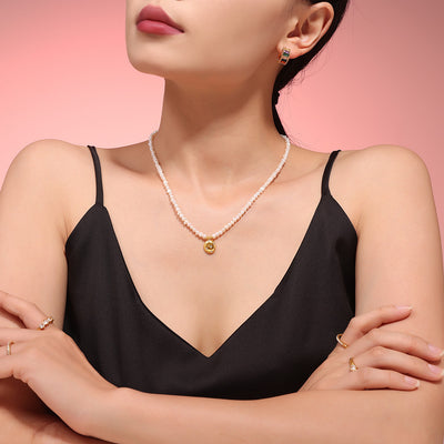 Model wearing freshwater pearl necklace with gold disc pendant