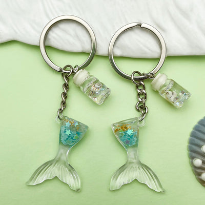 Image 1 showing two fish key chains with a glass bea and silver clasp.