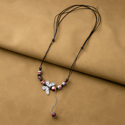 Speckled bead butterfly pendant necklace on brown fabric surface