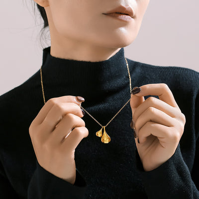 Gold dual teardrop pendant necklace worn on black turtleneck