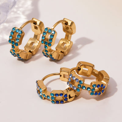 Blue square-link zircon huggies open and closed on table