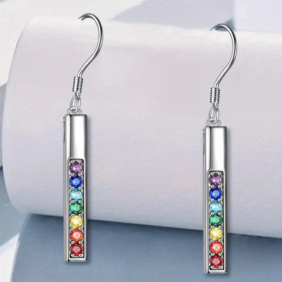 Pair of silver bar drop earrings with rainbow stones on white roll backdrop
