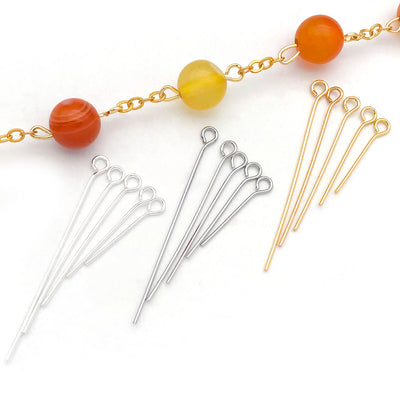 Gold-tone eye pin jewelry findings arranged on a light background