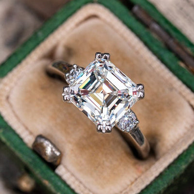 Asscher-cut CZ three-stone ring displayed in open green velvet ring box