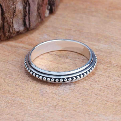 Antique silver beaded edge band ring on wood near bark