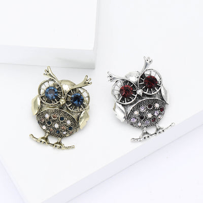 Gold and silver owl brooches with crystal eyes on white blocks