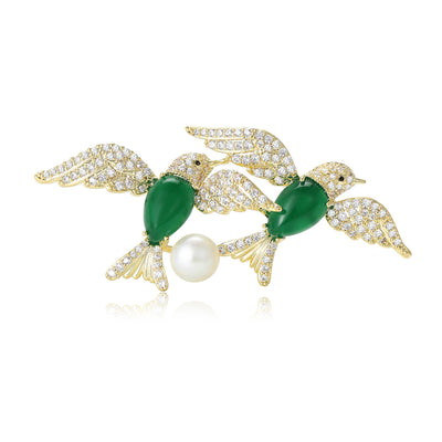Front view of two facing crystal birds with green oval bodies and pearl accents