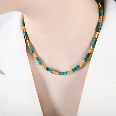 Green natural stone tube bead necklace with gold beads worn on collarbone