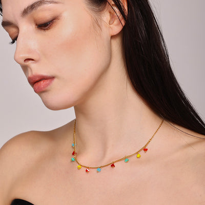 Model looking down wearing gold multicolor crystal drop necklace