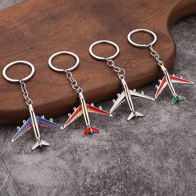 Four silver-tone airplane keychains displayed together with different colored accents.
