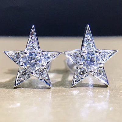 Pair of silver tone crystal five-point star stud earrings on light surface