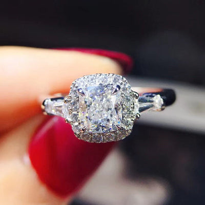 Silver princess-cut CZ halo ring front view held in fingers