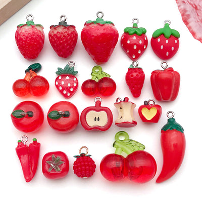 Multicolor apple and strawberry charms arranged on a light background