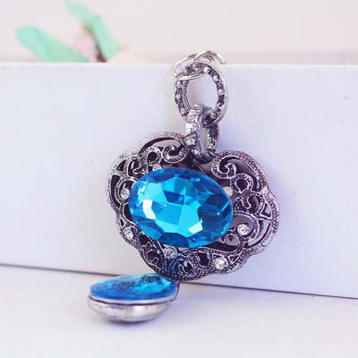 Close-up angled view of the blue faceted oval pendant and filigree metal frame.