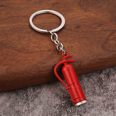 A large plain red fire extinguisher keychain rests on a wooden surface.