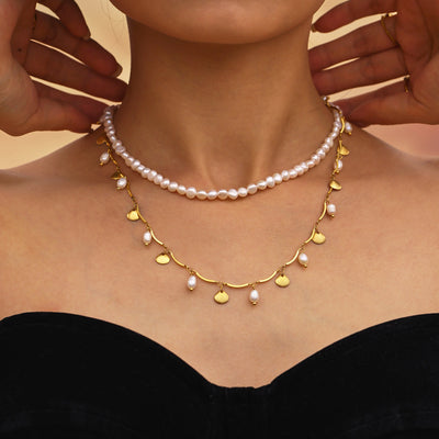 Model wearing baroque pearl choker layered with gold shell pearl necklace