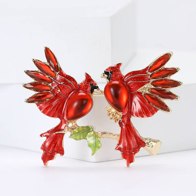 pair of red cardinal birds enamel brooch with green leaves isolated on a white background