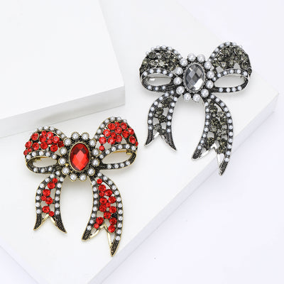 A looped bow set with crystals and a central oval stone shown on a white background