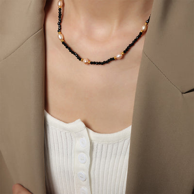 Black bead pink pearl gold accent necklace worn with beige blazer and white top