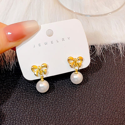 Primary supplied view of gold bow pearl-look stud and clip earrings
