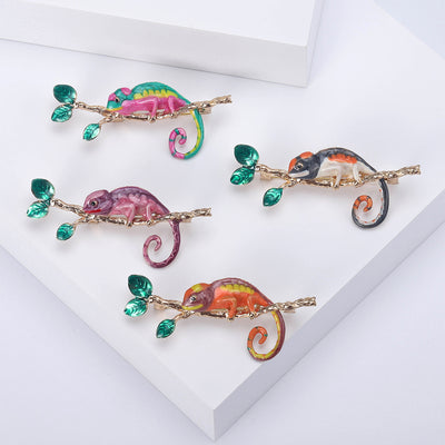 Product display showing a long-tailed chameleon perched on a leafy crystal branch
