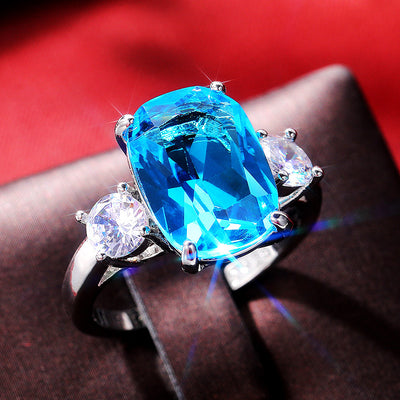 Silver ocean blue oval three-stone ring red backdrop