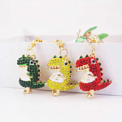 Three rhinestone dinosaur ornaments in green, yellow and red with gold-tone clips.
