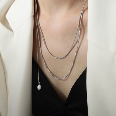 Silver double snake chain necklace with pearl drop worn on model