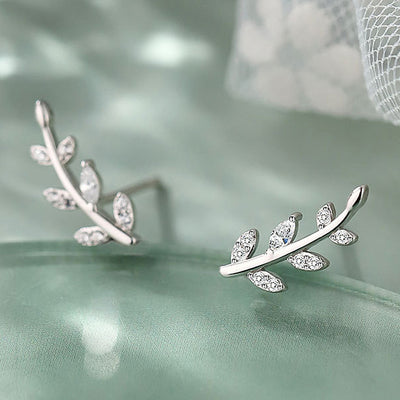 Silver leaf branch climber clear CZ stud earrings on green fabric