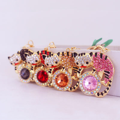 Four gold-tone rhinestone cat charms in black, red, brown and pink are arranged in a row.